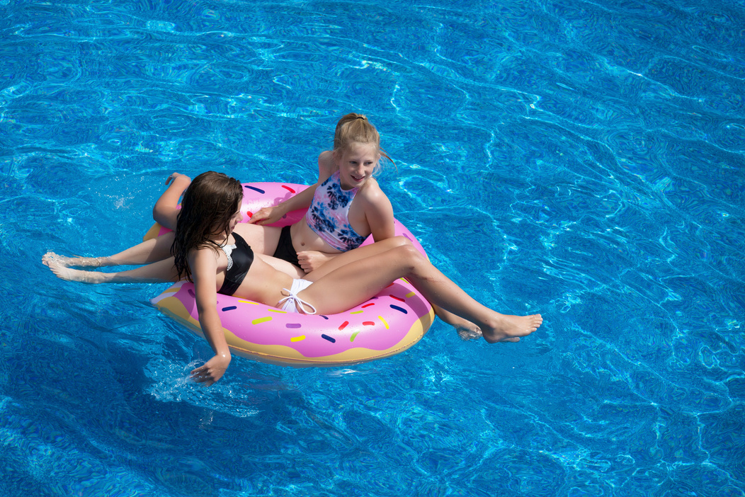 Two Girls Sitting on Pink Doughnut Pool Float
